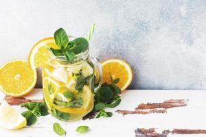 Lemonade drink of soda water, lemon and mint leaves in jar on light background. Copy space photo