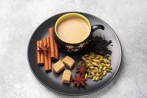 Indian drink masala tea with milk and spices. Cardamom sticks cinnamon star anise cane sugar. Concrete grey table copy space. photo