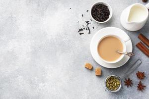 Indian drink masala tea with milk and spices. Cardamom sticks cinnamon star anise cane sugar. Concrete grey table copy space.
