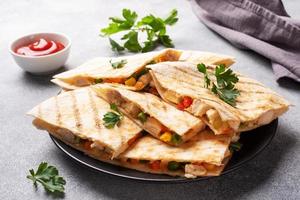Triangular slices of a Mexican quesadilla with the sauce. The traditional dish of Mexico is tortillas stuffed with meat and vegetables. copy space. photo