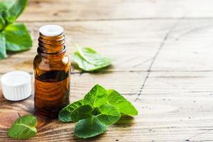 Essential aroma oil with peppermint on wooden background. Selective focus, copy space. photo