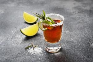 Glass with alcohol, salt and lime on a dark concrete background. Cognac whiskey tequila. The concept of the party. Selective focus. Copy space. photo