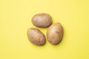 Raw potato tubers on a yellow background.