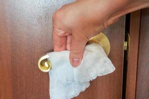 woman cleans the door handle with a napkin. Disinfection of surface microbes and viruses. photo