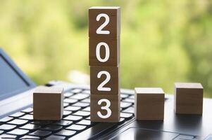 New year 2023 on wooden blocks on top of a laptop - Copy space and New Year concept photo