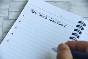Hand writing New Year's Resolutions text on notepad. New beginning concept photo