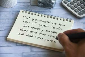 Life inspirational quote - Put yourself at the top of your to-do list every single day and the rest will fall into place. Hand writing on notepad photo