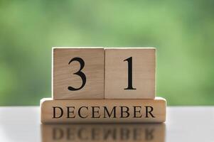 31 de diciembre texto sobre bloques de madera con fondo de naturaleza borrosa. concepto de calendario foto