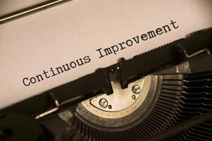 Side view of continuous improvement text on an old typewriter in vintage color. Business concept photo