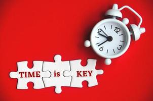 Text on missing jigsaw puzzle with alarm clock background - Time is key. photo