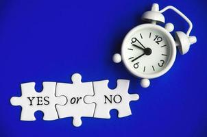 Text on missing jigsaw puzzle with alarm clock background - Yes or No. photo