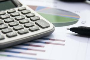 Analysis of data, chart and graphs with calculator and pen. Business finances concept photo