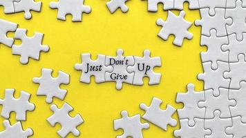 Top view of motivational quote on yellow cover - Just do not give up with jigsaw puzzle missing pieces background. photo