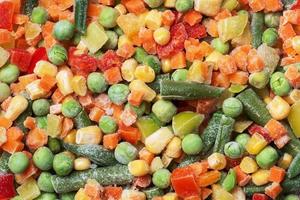 Chopped frozen vegetables background. Corn peas pepper carrots photo