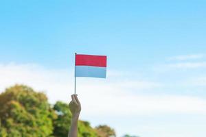 hand holding Indonesia flag on blue sky background. Indonesia independence day, National holiday Day and happy celebration concepts photo