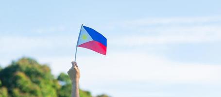 mano sosteniendo la bandera de filipinas en el fondo de la naturaleza. 12 de junio del día de la independencia y conceptos de celebración feliz foto