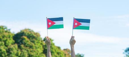 mano sosteniendo la bandera jordana en el fondo de la naturaleza. día de la independencia de jordania y conceptos de celebración feliz foto