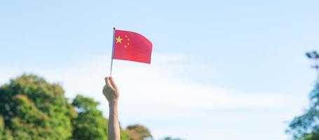 mano que sostiene la bandera china sobre fondo de cielo azul. día nacional de la república popular de china, día festivo de la nación pública y conceptos de celebración feliz foto