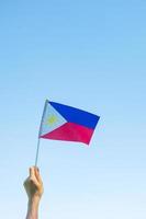 mano sosteniendo la bandera de filipinas en el fondo de la naturaleza. 12 de junio del día de la independencia y conceptos de celebración feliz foto