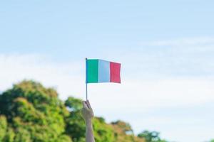 mano sosteniendo la bandera de italia en el fondo de la naturaleza. día nacional, día de la república, festa della repubblica y conceptos de celebración feliz foto