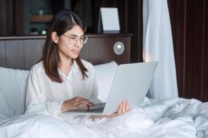 Happy woman using laptop for work, female meeting  online by computer notebook on bed. technology, network, work from home, lifestyle and digital communication concept photo