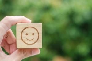 símbolo de cara de emoción de sonrisa en bloques de madera. calificación de servicio, clasificación, revisión del cliente, satisfacción, evaluación y concepto de retroalimentación foto