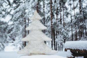 White artificial fir tree stands on wooden branch, covered with snow. Christmas or New Year decor. Season concept. Beautiful winter landscapes. Frosty weather photo