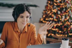 consultora de callcenter en auriculares hablando con el cliente mientras trabaja durante las vacaciones de navidad foto