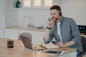 Smiling young man listening attentively to lecture online at home photo