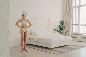 Healthy slender young woman in white underwear on scales photo