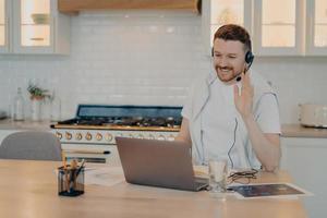 Happy young man having lesson during elearning on laptop at home photo