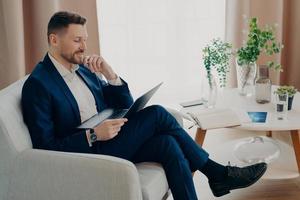 Young executive manager relaxing while working on his computer in living room photo