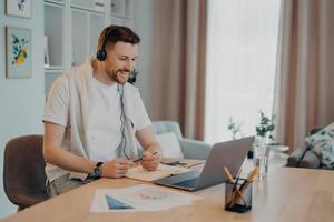Smiling young male in headset studying at home during quarantine photo