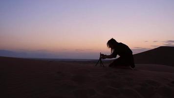 mujer caucásica viajera turística en gira por el desierto captura momentos de viaje con un smartphone en un trípode tarde. creador de contenido de vacaciones al aire libre video