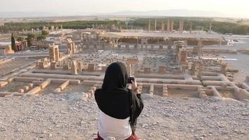 mulher em viagens de hijab tira foto do panorama de persépolis - antiga cidade persa permanece video