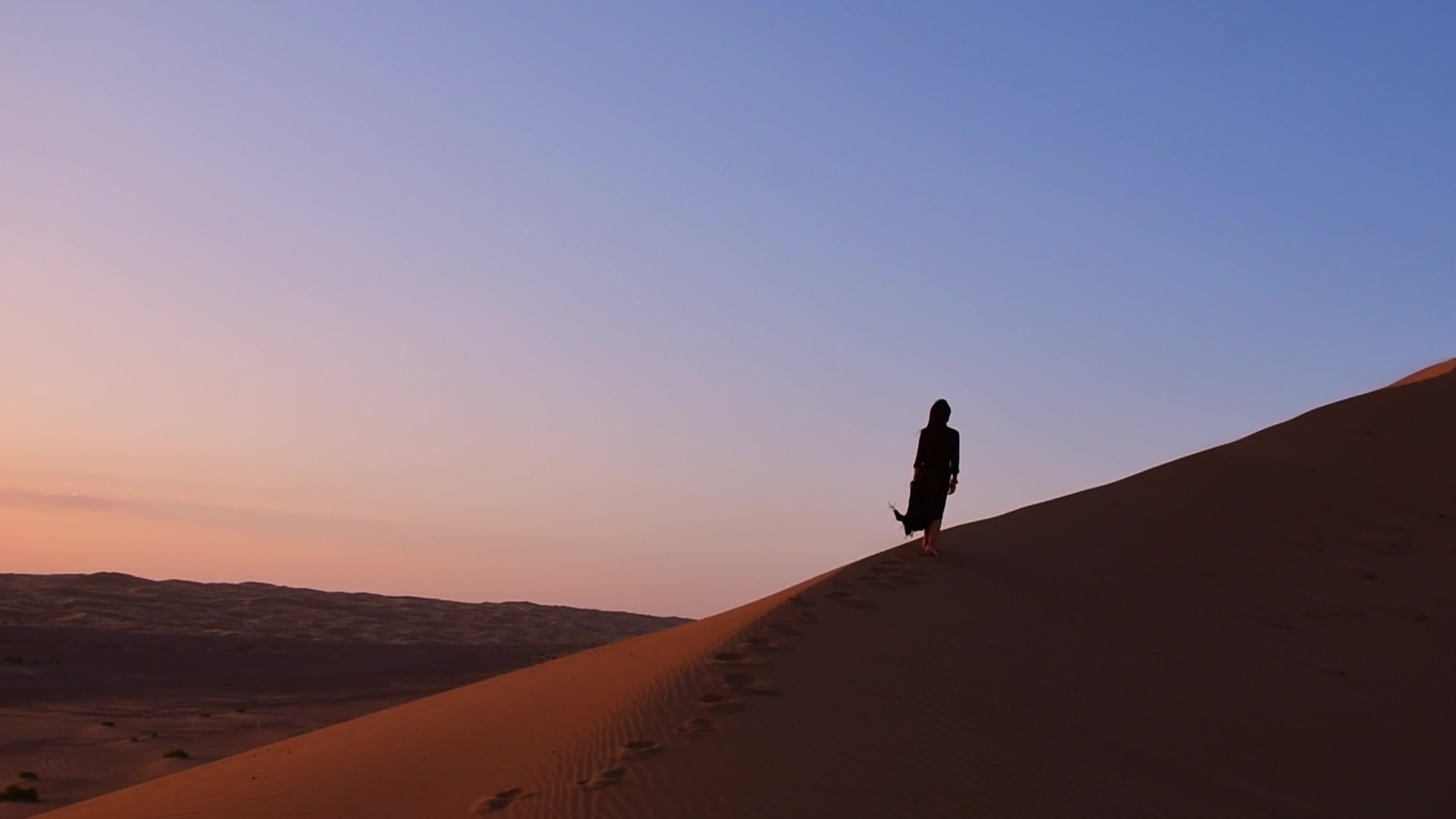 Young beautiful woman in long dress walks along sand dunes in iran ...