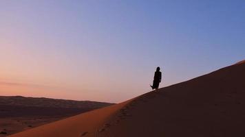Joven mujer hermosa con vestido largo camina por las dunas de arena en el desierto de Irán Kashan