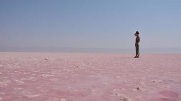puesto turístico de mujer caucásica en la orilla del lago salado rosa maharlu. destino de viaje irán en shiraz video