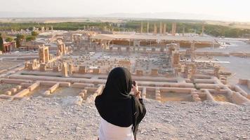 mujer en viaje hijab toma una foto del panorama de persépolis - restos de la antigua ciudad persa