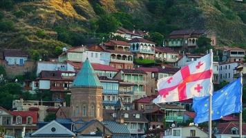 EEU and Georgia flags in Europe square, Tbilisi with background of old town historical houses. Georgia integration to EU concept video