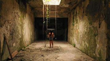 Young caucasian woman standing in abandoned passage tunnel alone looking up to light. Tskaltubo exploration historical Georgia travel landmark video