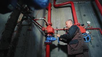 Ukraine Rivne 10.04.2022 The engineer opens the water supply valve for fire extinguishing systems. Industrial water supply pipes. Overlap or water supply.