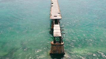 Broken bridge running over ocean surface in Florida Keys, USA. Above aerial view from drone of old Bahia bridge along ocean surface with panoramic oceanscape. Concept of architecture video