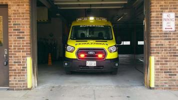 Chicago Illinois 12.04.2022 ambulance voertuig in de garage van de afdeling spoedeisende hulp van het ziekenhuis. vooraanzicht met zoom van gele ambulance met knipperende lampjes, klaar om te vertrekken uit het ziekenhuis video