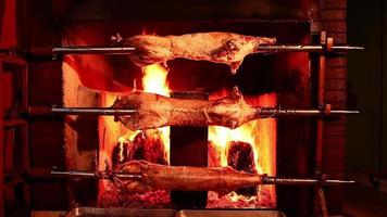 Lamm im Holzfeuer kochen. Lammfleisch, das um ein heißes Feuer gekocht wird. video