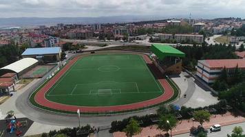 Green smooth carpet soccer field. Aerial view of green astroturf pitch in the middle of the city.