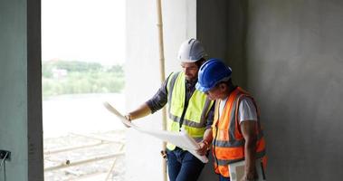 A Caucasian male and Asian old  man civil engineers looking at blueprint . video