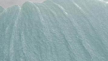 bem-vindo às ilhas virgens. a inscrição no fundo de areia, que é levada pelas ondas do mar. protetor de tela. ondas lavam a areia. fundo do mar arenoso através de águas claras. video