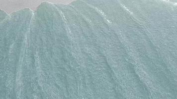 Willkommen auf Borabora. die Inschrift auf dem Hintergrund aus Sand, der von den Wellen des Meeres weggespült wird. Bildschirmschoner. Wellen spülen den Sand weg. sandiger Meeresboden durch klares Wasser.