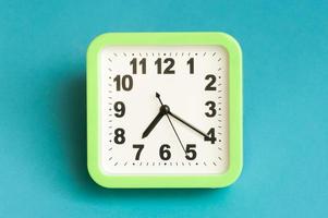 Minimal flat lay concept. Green analog clock on blue background. photo